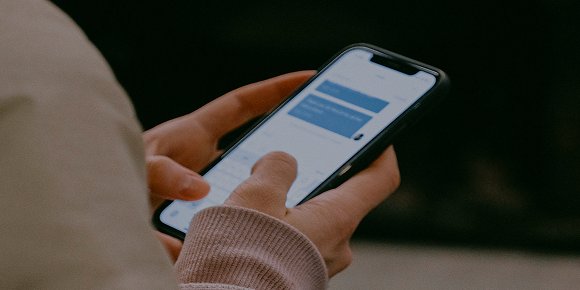A persons hands holding a mobile phone with text messages on the screen.